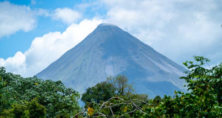 Uitzicht op de Arenal vulkaan gedeeltelijk bedekt door wolken op een zonnige dag.
