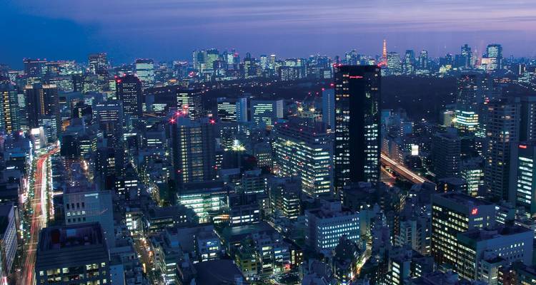 Paisaje nocturno urbano de Tokio con edificios iluminados.