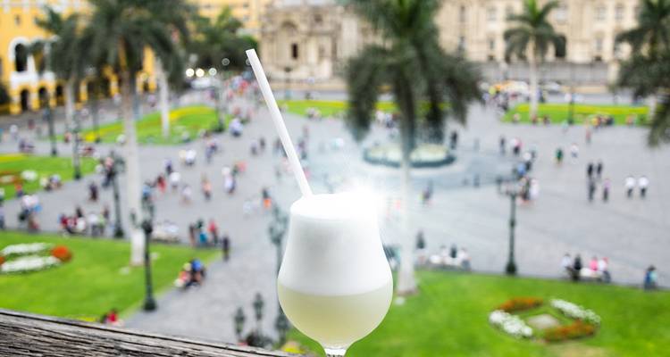 Verre de cocktail surplombant une place de ville animée remplie de gens.