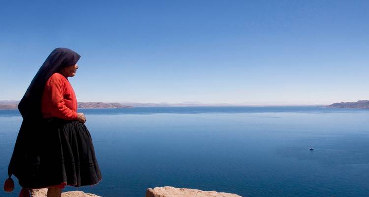 Une femme qui surplombe un vaste lac sous un ciel bleu dégagé.