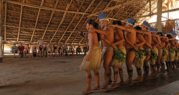 Danza tradicional interpretada por pueblos indígenas en un edificio de paja.