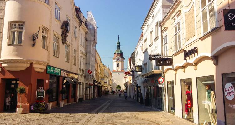 Straßenansicht mit Geschäften und einem Kirchturm.