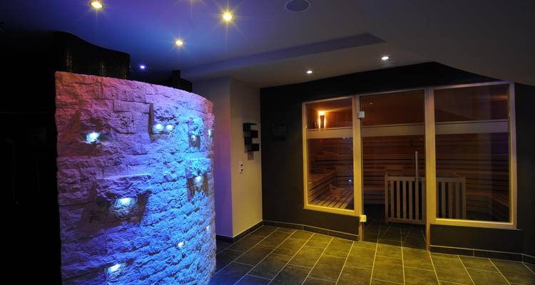 Área de relajación interior con iluminación colorida y sauna.