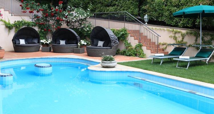Área de piscina al aire libre con tumbonas y vegetación exuberante.