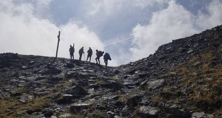 Grupo de excursionistas silueteados contra el cielo en un sendero montañoso escarpado.