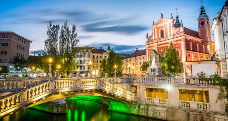 Vista panorámica de un puente iluminado y edificios históricos a lo largo de un río.