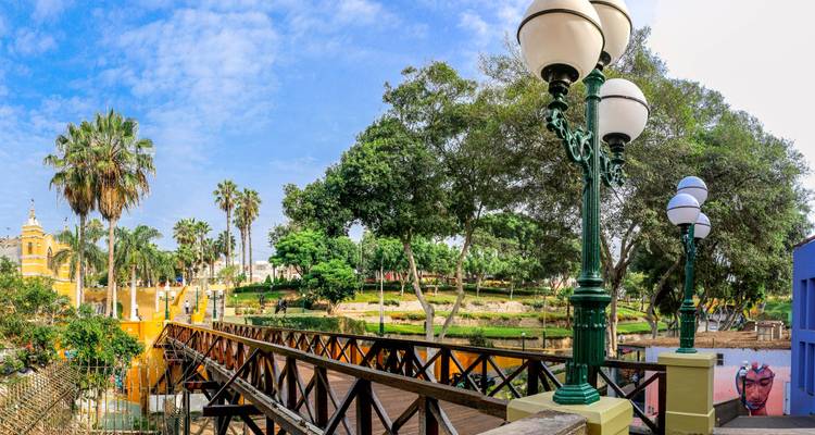 Parque pintoresco con puente de madera y farolas vintage.
