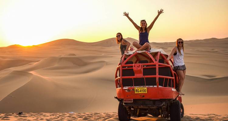 Mensen op een buggy in een woestijn tijdens zonsondergang.