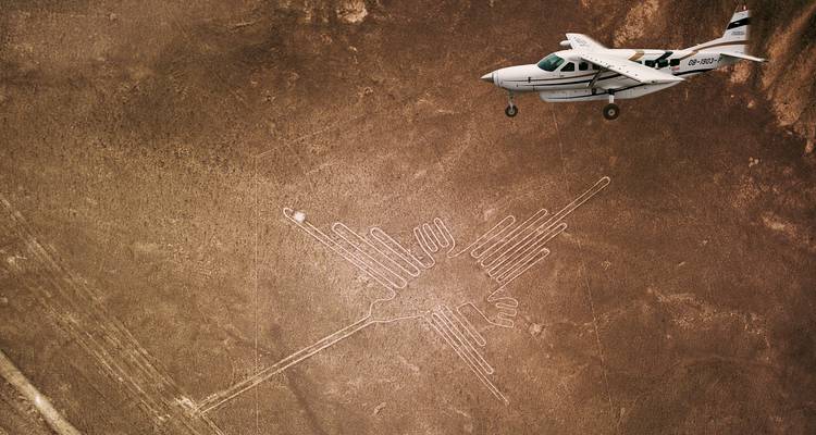 Vue aérienne des lignes de Nazca avec un petit avion au-dessus.