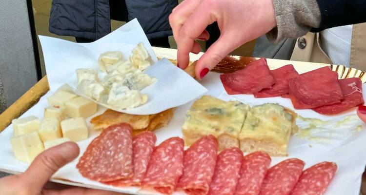 Close-up van een antipastoschotel met diverse kazen, salami en gedroogde vleeswaren die gedeeld worden.