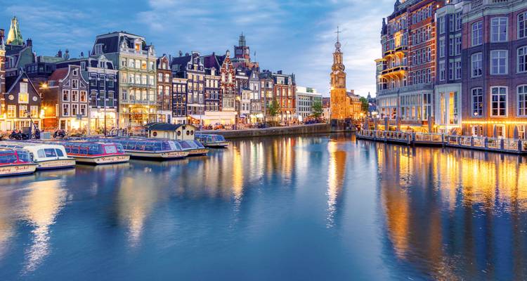 Escena tradicional de canal de Ámsterdam con edificios históricos y barcos.