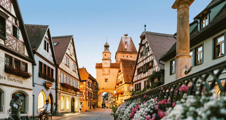 Charmante Kopfsteinpflasterstraße, die zu Rothenburg ob der Taubers ikonischem Plönlein-Turm im frühen Abendlicht führt.