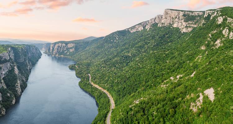 Vue aérienne spectaculaire des gorges des Portes de Fer où le Danube serpente entre d'escarpées falaises boisées au coucher du soleil.