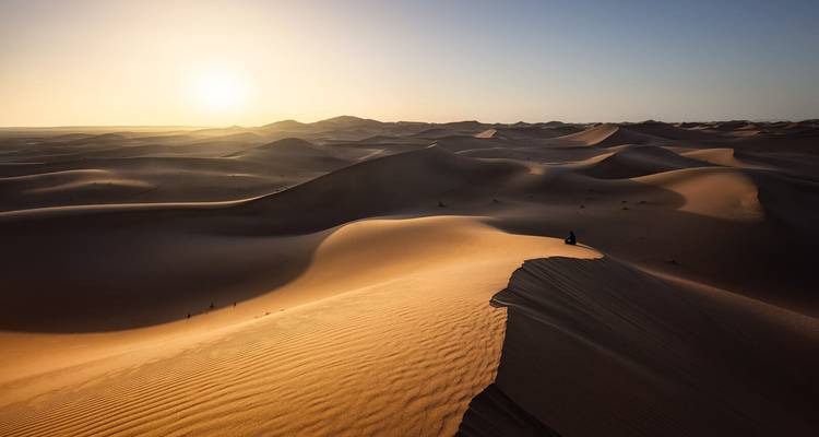 Vaste paysage désertique avec des dunes ondulantes au coucher du soleil.