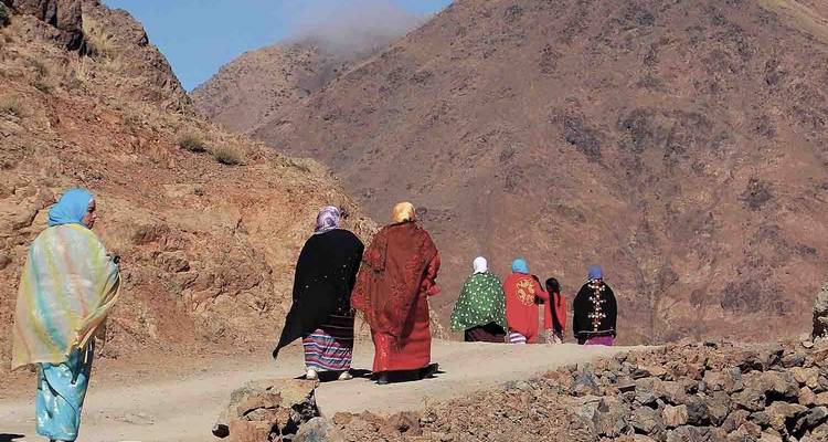 Groupe de personnes vêtues de tenues traditionnelles marchant dans un paysage rocheux.