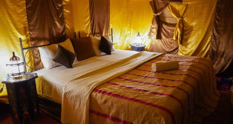 Intérieur de tente luxueux avec un lit et des décorations ornées.
