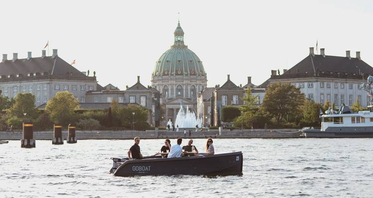 Un grupo de personas en un paseo en barco con un edificio histórico de fondo.