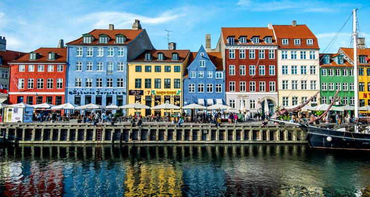 Edificios vibrantes a lo largo del paseo marítimo de Nyhavn bajo un cielo azul despejado.