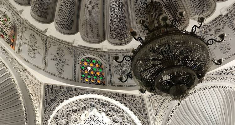 Eine verzierte Decke mit detaillierten Mustern und einem großen Kronleuchter.