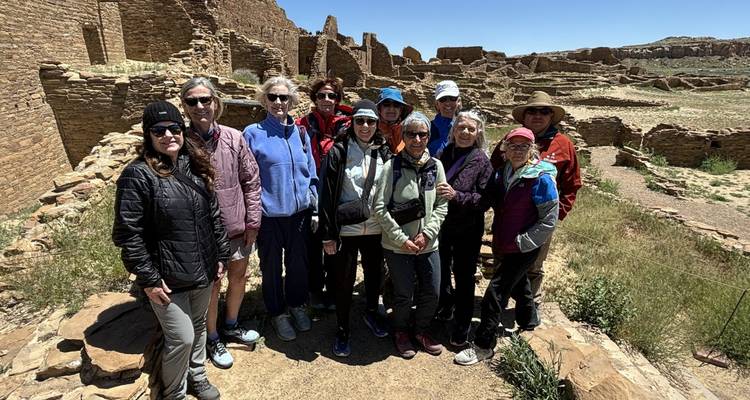 Un grupo de personas posando frente a antiguas ruinas de piedra.