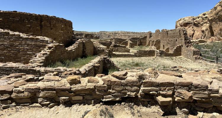 Antiguas ruinas de piedra en un paisaje árido bajo un cielo azul despejado.