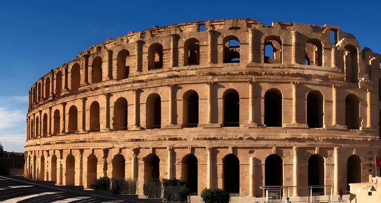 Un gran anfiteatro antiguo bajo un cielo azul despejado.