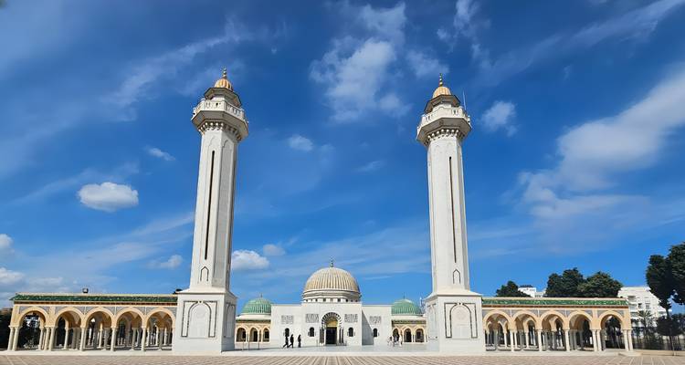 Una mezquita with grandes cúpulas blancas y altos minaretes contra un cielo azul claro.