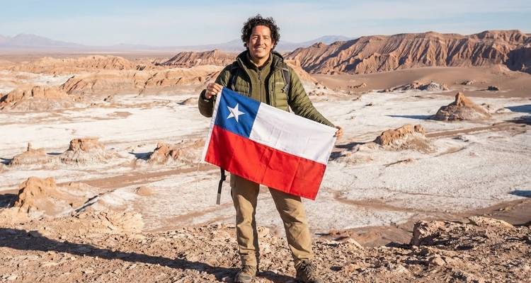 Persona sosteniendo bandera chilena con paisaje desértico