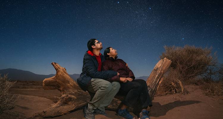 Pareja observando las estrellas juntos en un desierto