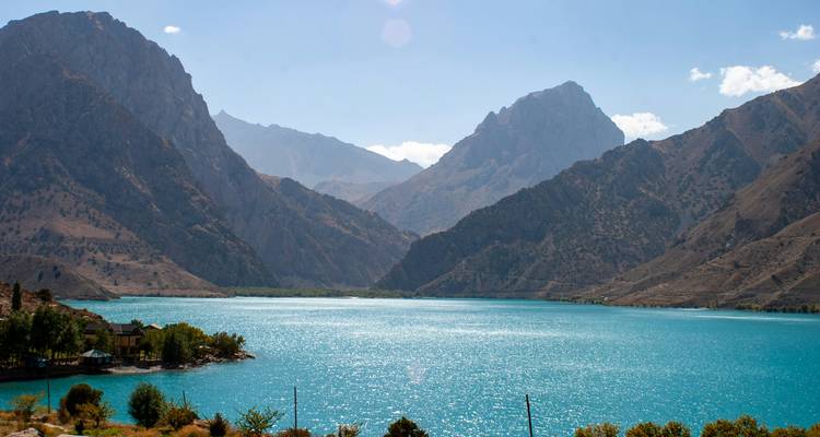 Leuchtend türkiser See, umgeben von aufragenden Berggipfeln unter einem klaren blauen Himmel.