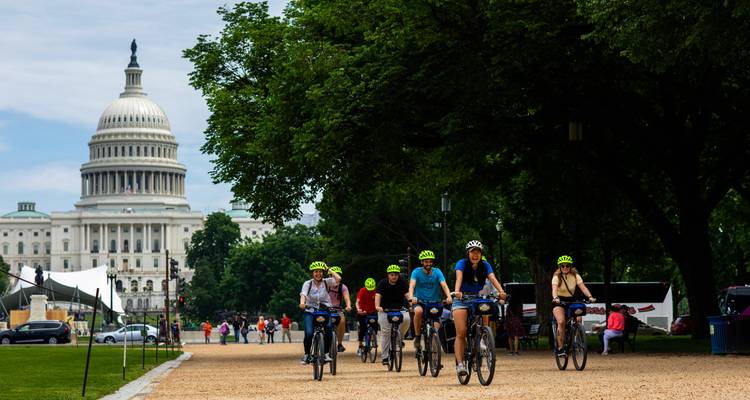 Cyclistes roulant près du Capitole américain sur le National Mall, des arbres feuillus encadrant le dôme historique