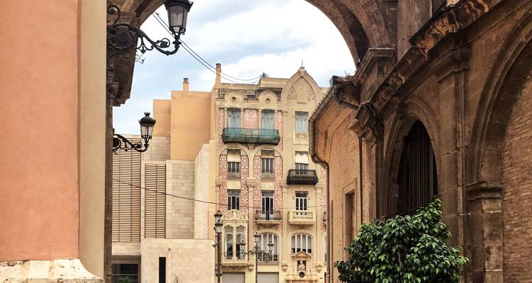 Architectural alleyway framed by stone arches and ornate Spanish apartment facades.