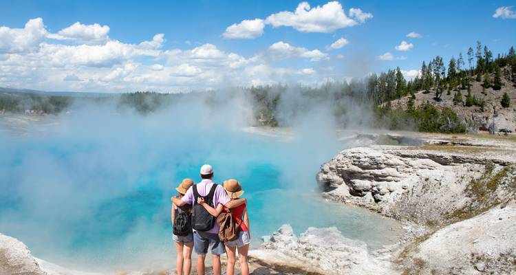 Familia observando una piscina geotermal azul humeante en el Parque Nacional de Yellowstone.
