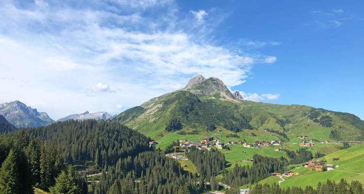 Exuberantes montañas verdes y bosques que rodean un pequeño pueblo.