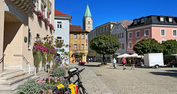 Place de ville charmante avec des bâtiments colorés et des gens qui se promènent.