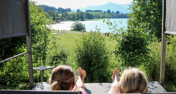 Deux personnes se détendant au bord d'un lac sous un ciel ensoleillé.