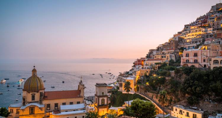 Un pueblo en la ladera con edificios coloridos con vista al mar durante el crepúsculo.