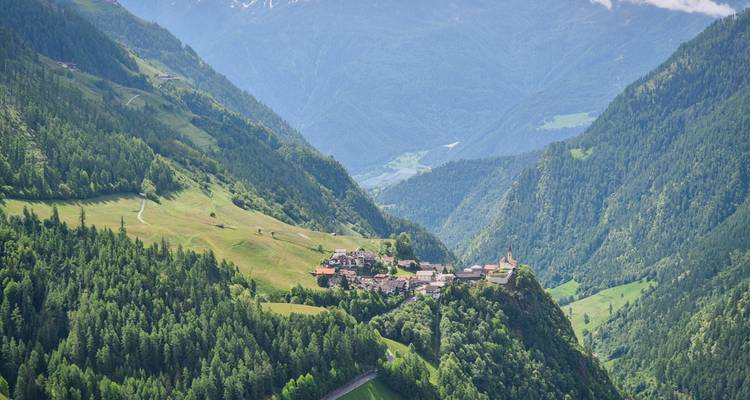 A picturesque village nestled in a valley surrounded by lush mountains.