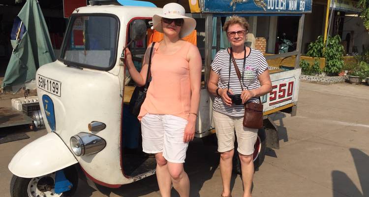 Zwei Frauen posieren bei einem Tuk-Tuk an einem sonnigen Tag.