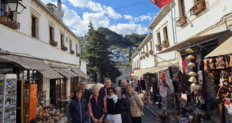 Grupo de personas posando en una calle encantadora con edificios antiguos y un fondo montañoso.