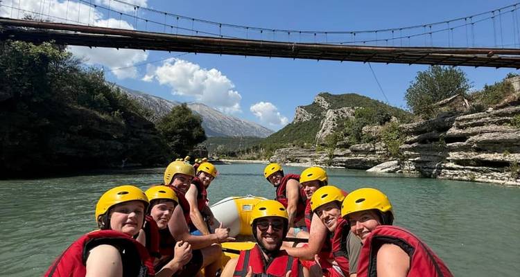 Grupo de personas con cascos amarillos disfrutando del rafting en un río.