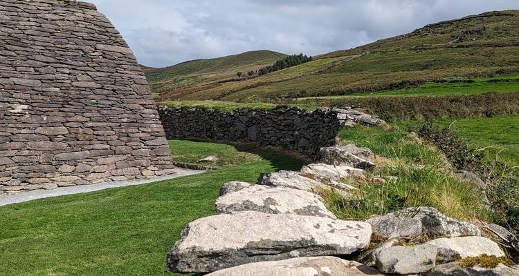 Stone early-Christian Oratory wall framed by rolling green hills in Kerry