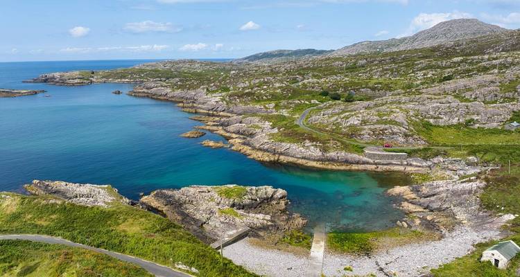Turquoise inlet surrounded by rugged granite coastline and rolling hills on the Beara Peninsula