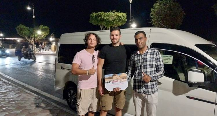 Tres hombres posando frente a una camioneta por la noche.