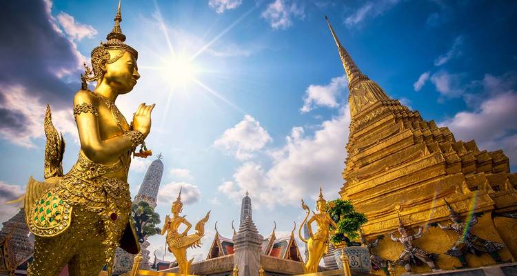 Statue dorée et chedi orné au Grand Palais de Bangkok rayonnent sous un soleil éclatant.