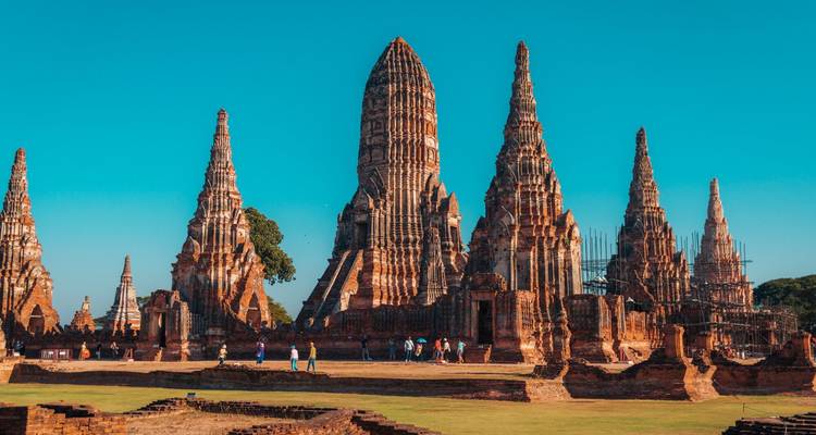 Les tours de briques rouges du Wat Chaiwatthanaram se dressent fièrement contre un ciel bleu limpide d'Ayutthaya.