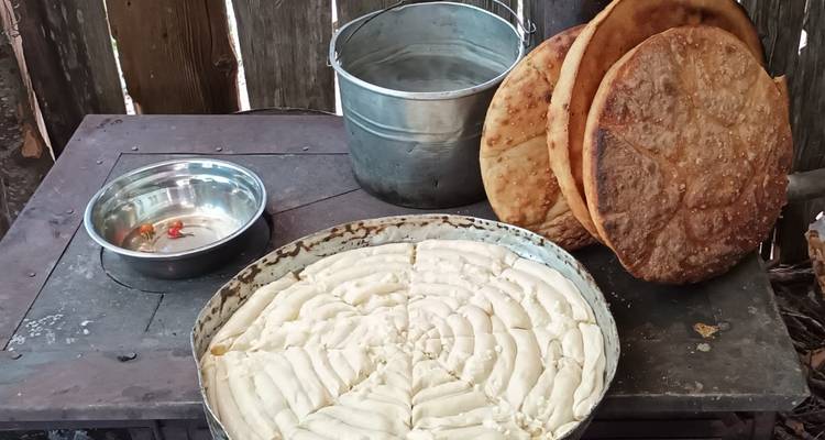 Comida tradicional albanesa exhibida en una estufa de madera, incluyendo panes planos y pasteles.