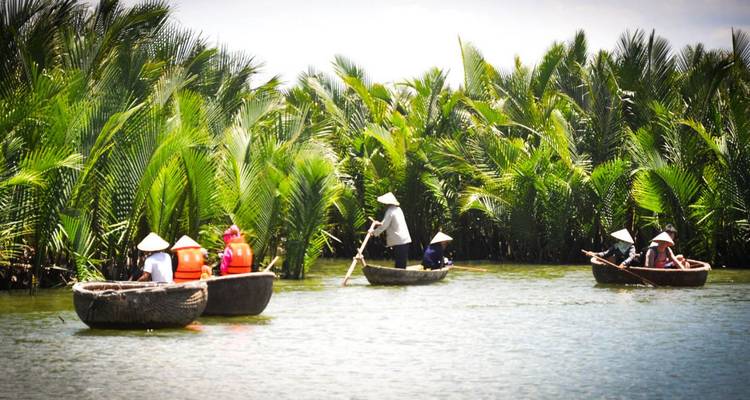 Multiple round basket boats with visitors paddling through a dense water-coconut forest.