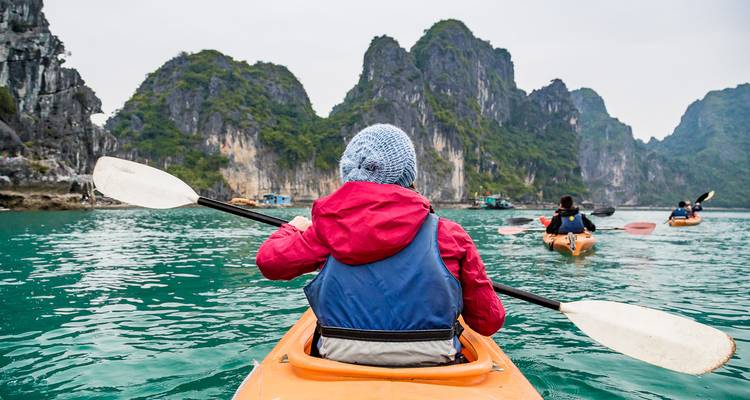 Les kayakistes pagaient à travers des eaux turquoise entre d'imposants karsts calcaires dans la baie d'Halong.