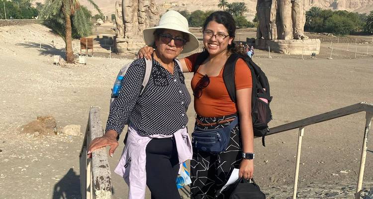 Mère et fille avec toile de fond montagneuse près de grandes statues.